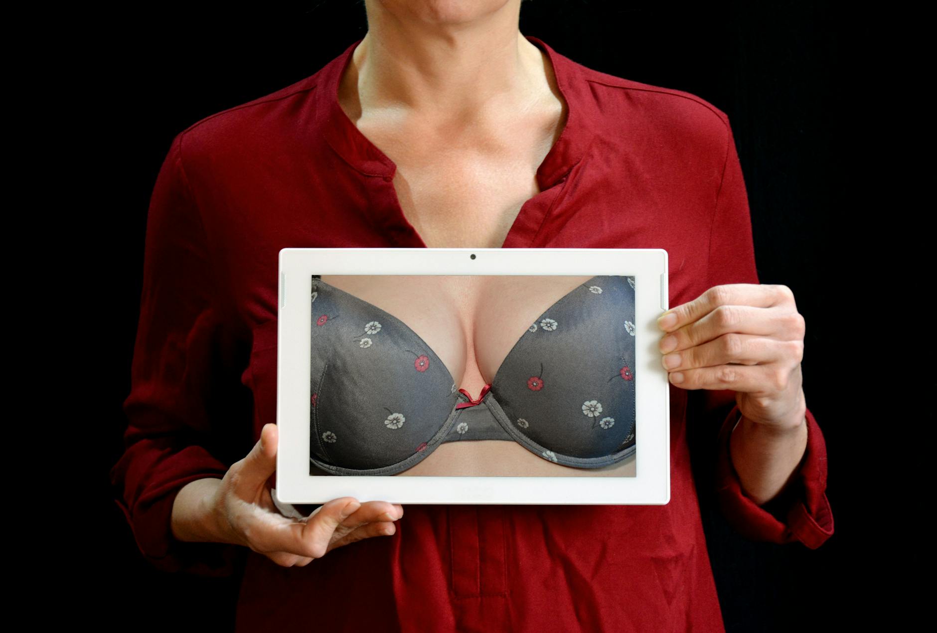 woman holding white tablet computer showing gray bra