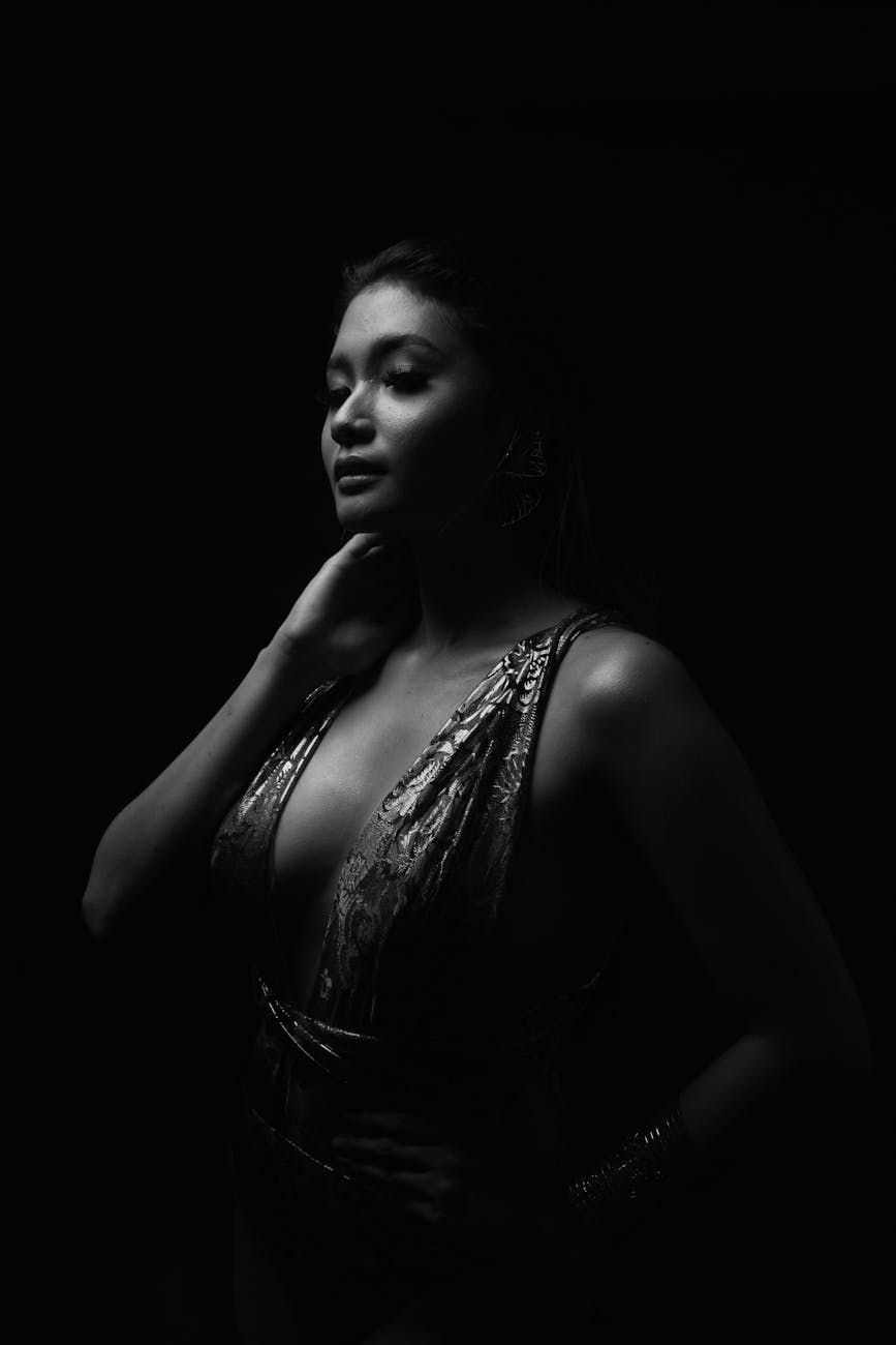 feminine asian model touching neck on black background